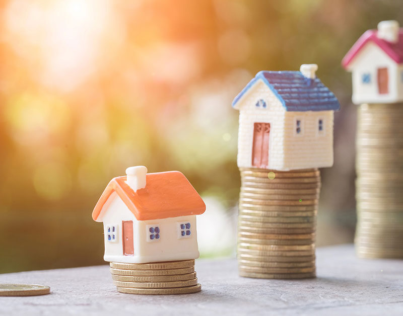 Häuser die sich auf gestapeltem Geld befinden